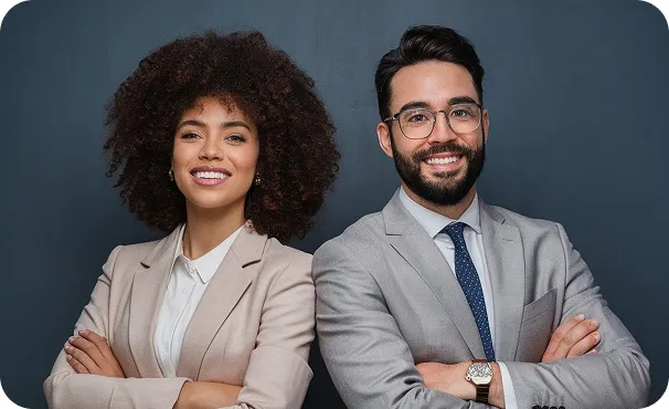 Uma mulher e um homem de roupa social, sorrindo de braços cruzados.