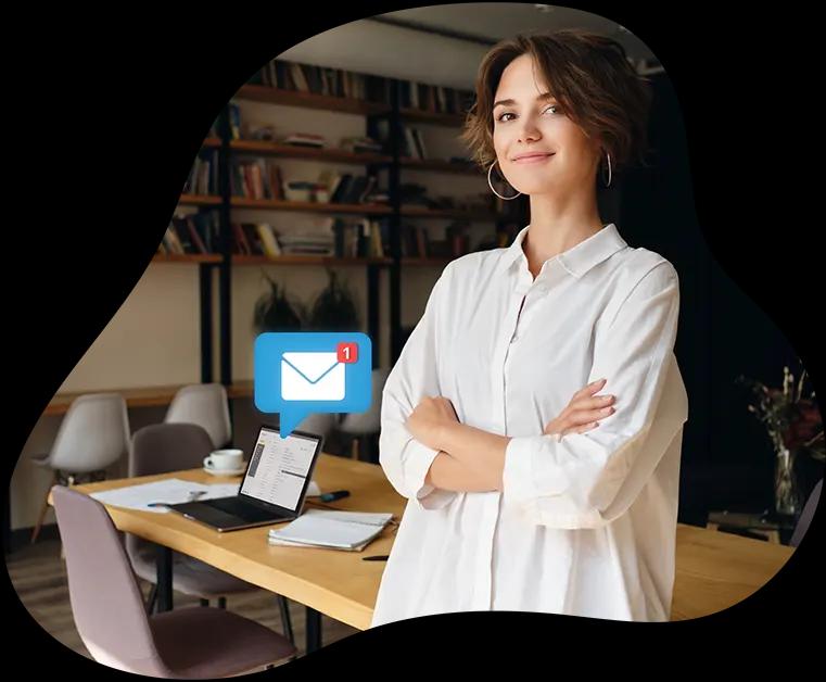 Serviço de e-mail corporativo da Task Imagem de mulher com braços cruzados com um notebook em cima de uma mesa em segundo plano